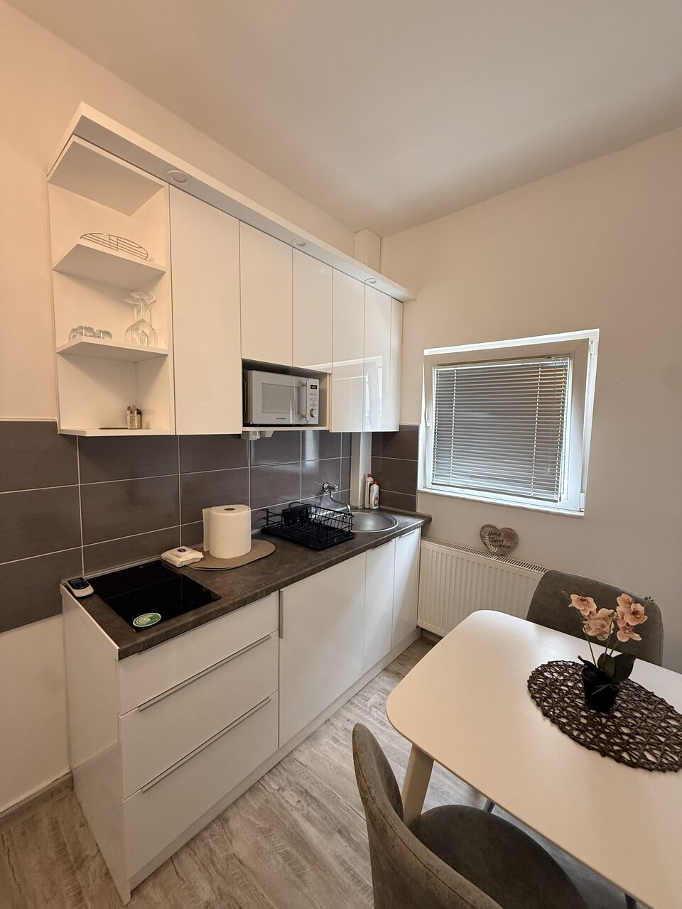 Fully equipped white kitchen with induction hob, microwave and dining table for two